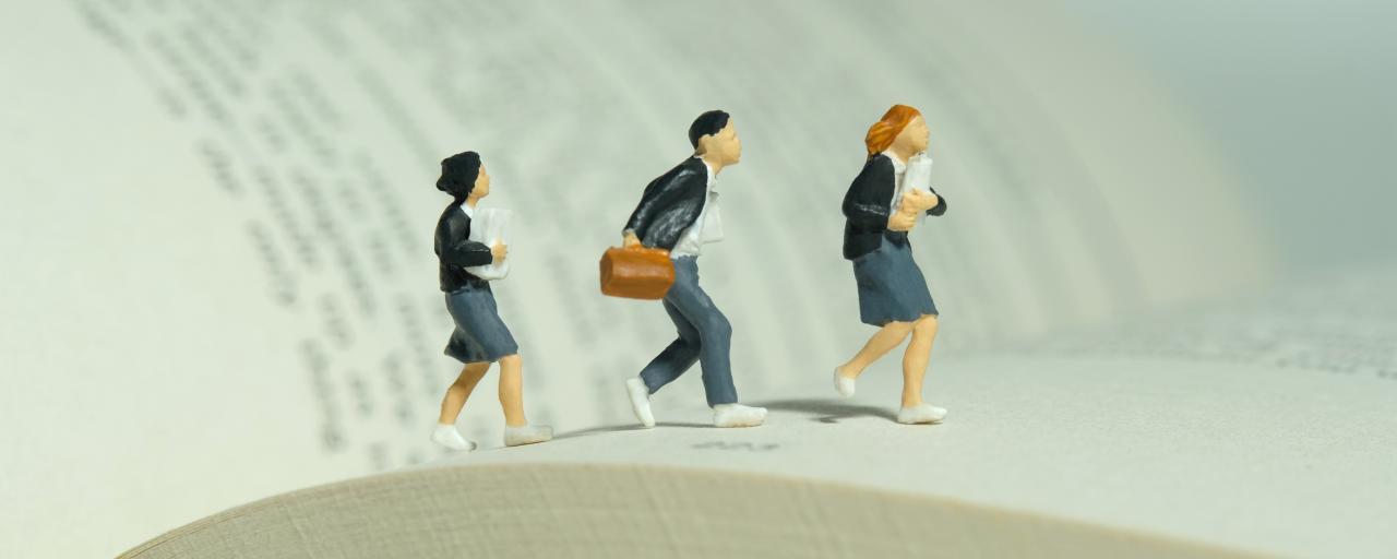 miniature people walking on a book